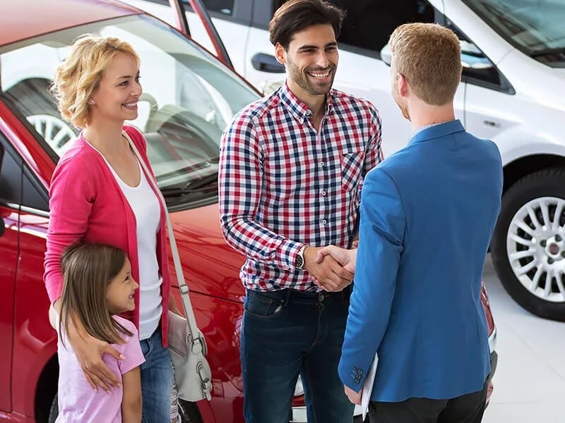 family talking with dealership salesman